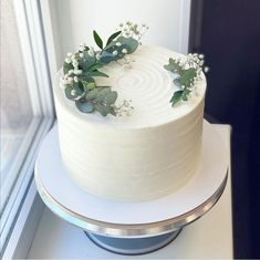 a white cake sitting on top of a table next to a glass window covered in frosting