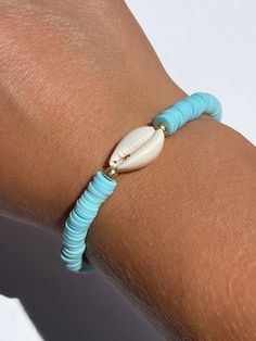 a close up of a person wearing a bracelet with shells on it's wrist