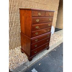 a tall wooden dresser sitting on the side of a road next to a brick wall