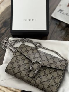 This Gucci Dionysus GG Supreme Chain Wallet Clutch is a stylish and functional accessory for women. The bag features a snap closure and a chain strap for easy carrying. The exterior is made of canvas and leather, with a beige GG pattern that is both classy and elegant. The bag has a small size of 8x5x2.3 inches, making it perfect for a night out or a casual day. The interior is lined with beige cloth and there are two compartments inside to store your essentials. The bag comes with an original box and dust bag and is in excellent condition. Classy And Elegant, Chain Wallet, Functional Accessories, Wallet Chain, Gucci Dionysus, Clutch Wallet, Chain Strap, Snap Closure, Bags Handbags