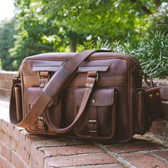 Our Roosevelt Leather Pilot Bag is crafted from water buffalo hide, with a green canvas lined interior, and genuine brass and iron hardware. It’s 16” long, 10” high, and 5” wide, the ideal size to hold a 15” laptop. Designed with four buckled exterior pockets and a roomy interior with zippered pockets, this bag is designed to securely hold the items you need to bring along on your travels. Built for comfort, this pilot bag has adjustable 2” wide shoulder straps, so you can comfortably carry it f Waxed Canvas Shoulder Bag Briefcase, Classic Brown Satchel For Outdoor, Waxed Canvas Satchel Laptop Bag, Outdoor Leather Shoulder Bag With Waxed Finish, Leather Laptop Bag With Waxed Finish For Outdoor, Classic Outdoor Bags With Waxed Finish, Leather Satchel With Waxed Finish For Everyday Carry, Leather Briefcase For Travel, Classic Waxed Canvas Satchel For Everyday Use