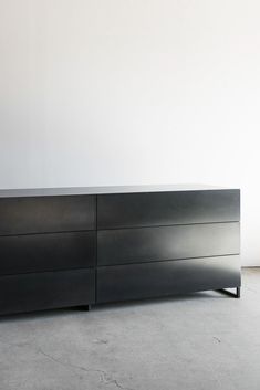 a large black dresser sitting on top of a cement floor next to a white wall