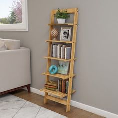 a living room with a white couch and book shelf next to a window in the corner