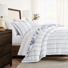 a bed with white and blue striped comforter in a bedroom next to a window