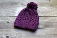 a purple knitted hat sitting on top of a wooden floor