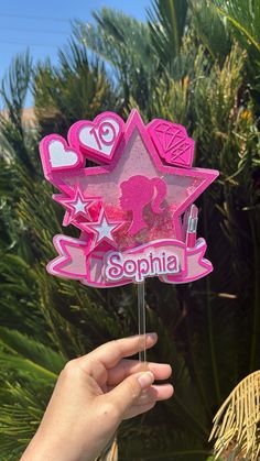 a hand holding up a pink pinata shaped like a star