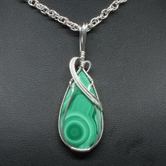 "Details About This Pendant: The contemporary stone pendant is hand crafted using fine precious metal wire and natural gemstone to form this stunning delicate enhancer. The bail is large enough to accommodate various styles of chains. It is not mass produced nor manufactured. *Natural Malachite Gemstone (30mm x 20mm Teardrop Shaped). *Pendant Size: 2 1/2\" long including bail x 3/4\" at widest point. Includes free 18\" chain. *Precious metal is lead free, nickel free, does not tarnish. To protec Green Agate Hand-wrapped Necklaces, Teardrop Agate Wire Wrapped Jewelry, Wire Wrapped Teardrop Agate Jewelry, Green Agate Hand Wrapped Necklaces, Green Hand Wrapped Agate Necklaces, Green Chrysocolla Pendant Jewelry, Gemstone Pendant In Silver-plated Wire, Malachite Pendant For Jewelry Making, Spiritual Gemstone Jewelry With Silver Plated Wire