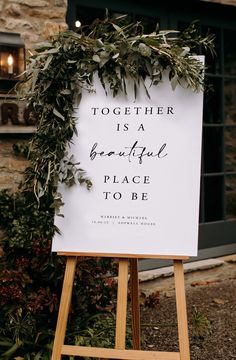 a welcome sign sitting on top of a wooden easel in front of a building