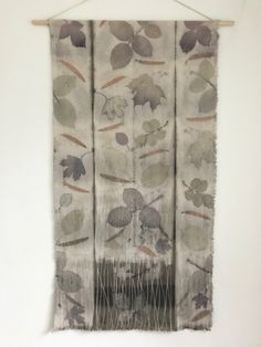 a piece of cloth hanging on a wall with leaves and branches printed on the fabric