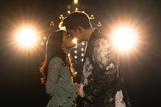 a man and woman kissing in front of bright lights