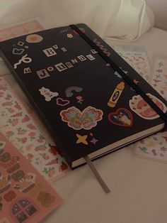 an open notebook sitting on top of a bed covered in stickers and paper decorations