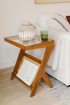 a white couch sitting next to a wooden table on top of a hard wood floor