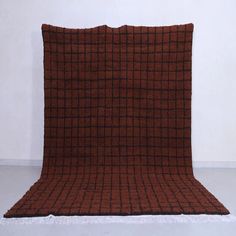 a brown and black blanket sitting on top of a white floor next to a wall