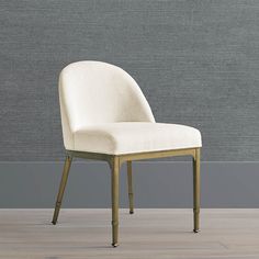 a white chair sitting on top of a hard wood floor next to a gray wall