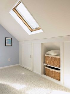 an attic bedroom with skylight and storage baskets in the closet area on the far wall