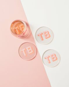 two glass coasters sitting on top of a pink surface