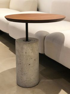 a concrete table with a wooden top in front of a white couch and coffee table