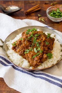 a silver plate topped with rice and meat covered in gravy on top of a wooden table