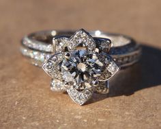 an engagement ring with a flower design on the side and two wedding bands around it