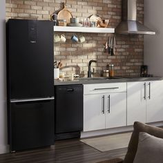 a black refrigerator freezer sitting next to a stove top oven under a brick wall