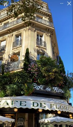 a tall building with lots of plants growing on it's sides and the words cafe de flore written in french