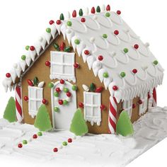 a gingerbread house decorated with candy canes and icing, on a white surface