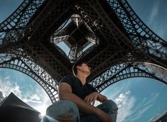 a man sitting on the ground in front of the eiffel tower