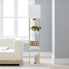 a living room with a white couch, lamp and bookshelf in the corner