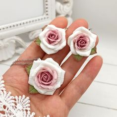 three small pink and white roses are held in someone's hand