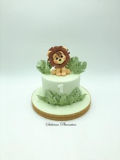 a cake with a lion on top and green leaves around the edges, sitting on a plate