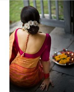 a woman sitting on the ground in front of a plate of food with flowers in her hair