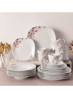 a table topped with lots of white plates and cups