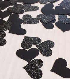 black and silver glittered hearts are scattered on a white tablecloth, as if for valentine's day