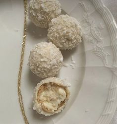 three desserts on a white plate with a gold chain