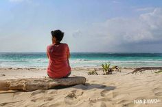 a person sitting on a log at the beach