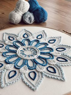 a close up of a piece of cloth on a table with yarn and balls in the background