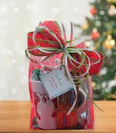 a gift bag filled with chocolates and wrapped in red ribbon next to a christmas tree