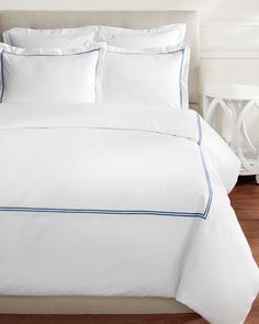 a bed with white sheets and blue trim