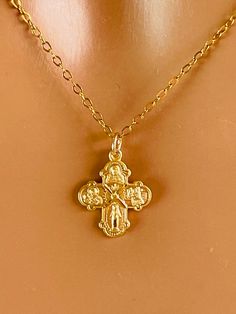 This is a dainty little gold four way cross charm necklace. This cute little cross is 14 karat gold over 925 sterling silver and hangs on a 14 karat gold filled chain. Spring clasp in back. Also available in 925 sterling silver, not shown. This small cross charm measures 15 X 13 mm and features Mary miraculous medal, Jesus Christ, Saint Christopher and Saint Joseph. Please be aware this is a very small charm. Chain is on a lovely shiny cable chain that sparkles with movement.  Model is wearing a Cross Necklace With Charms As Gift, Dainty Gold Crucifix Jewelry, Dainty Charm Necklaces With Miraculous Medal For Gifts, Dainty Charm Necklaces With Miraculous Medal As Gift, Dainty Miraculous Medal Charm Necklaces As Gifts, Gold Cross Charm Necklaces, Dainty Miraculous Medal Charm Necklace As Gift, Gold Cross Charm Necklaces In 14k Gold Filled, Dainty Cross Pendant Charms Jewelry