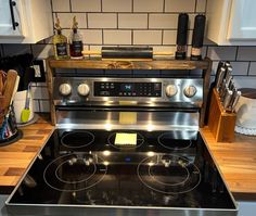 a stove top oven sitting inside of a kitchen next to a countertop with utensils on it