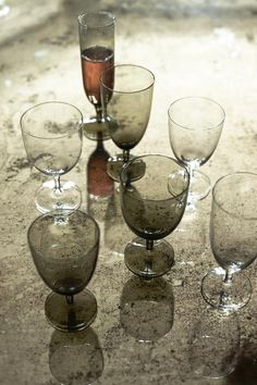 there are many wine glasses sitting on the table with one empty glass in front of them