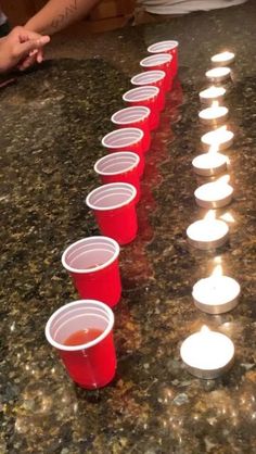 red cups are lined up with candles on the table