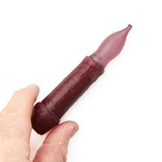 a person holding a lipstick tube in their left hand on a white background with space for text