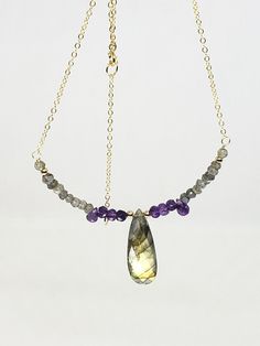 14k Yellow Gold Filled Labradorite Briolette and Amethyst Beaded Bar Necklace 16" + 2" extender This necklace features a 29x10mm pear briolette labradorite, 4mm labradorite rondelles and 6mm amethyst drops       DETAILS          Length:18"         Metal: 14k gold filled        Gemstone Bar size: 3.5"         Handmade         NOTE: I also take custom orders and can often do a similar piece or pendant if requested.w           Will ship safely packaged via USPS First Class. Thank you for your time and shopping by! Photos show magnified items to show details and therefore may appear larger than actual sizes. Please be aware of the real measurements stated in the description. Color may vary slightly due to the color calibration of each individual monitor. I'm more than happy to answer all of yo Elegant Briolette Gemstone Drop Necklace, Elegant Briolette Faceted Drop Necklace, Handmade Amethyst Briolette Necklace, Purple Amethyst Briolette Necklace, Amethyst Jewelry Necklace, Purple Briolette Faceted Necklace, Bead Bar Necklace, Necklace Inspiration, Bead Bar