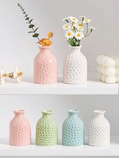 four vases with flowers in them sitting on shelves