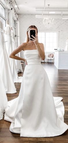 a woman in a white wedding dress taking a selfie