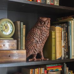 an owl statue sitting on top of a book shelf