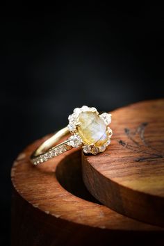 a yellow diamond ring sitting on top of a wooden table