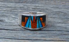 This band ring is handcrafted with Sterling Silver and beautifully inlaid with bright , dazzling, Fire Lab Opal and Onyx. As is seen in this work of art, the artist's talent is evident! It is a favorite due to the expertly clean cut geometric work, followed by the angular shape of the ring. This is that signature accessory that will compliment your wardrobe. We are proud to offer the David Rosales Collection of fine Native American Indian Jewelry. He has built a reputation for the finest inlaid Unique Multicolor Rings With Polished Finish, Unique Sterling Silver Opal Inlay Ring, Unique Sterling Silver Opal Ring With Inlay, Unique Opal Ring With Inlay For Gift, Southwestern Style Rings With Inlay As Gift, Southwestern Style Rings With Inlay For Gift, Artisan Multicolor Rings With Inlay, Artisan Multicolor Inlay Rings, American Indian Jewelry