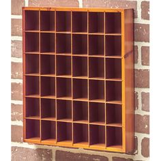 a wooden shelf with many compartments on the side of a brick wall in front of a window